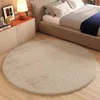 A round beige rug in a bedroom setting, next to a bed and a nightstand. Anteprima dell’immagine prodotto