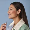 A woman wearing headphones and a jacket against a blue background. Anteprima dell’immagine prodotto