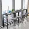 A bar table and stools set up by a large window overlooking a city skyline. Podgląd zdjęcia produktu