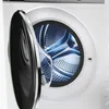Close-up view of the open door of a white washing machine, showing the stainless steel drum. Produktbild-Vorschau
