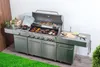 A stainless steel gas grill kitchen setup with food cooking on the grill, placed on a wooden floor with artificial grass in the foreground. Podgląd zdjęcia produktu