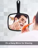 A man is shaving in front of a mirror, which is hanging on a tiled wall. Produktbild-Vorschau