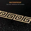 A close-up of gold geometric Greek key pattern stickers on a black, wet surface. Náhľad obrázku produktu
