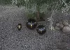 Three dark, spherical decorative lights are placed on a gravel ground under a tree. Produktbild-Vorschau