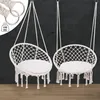Two white macrame hanging chairs with cushions are displayed against a dark background. Náhled obrázku produktu