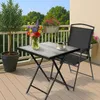 A small square table and chair set on a balcony with flowers and a tree. Produktbild-Vorschau