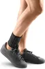 A person's legs wearing a black ankle brace and black sneakers. Produktbild-Vorschau