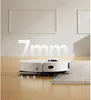 A white robot vacuum cleaner is shown on a wooden floor, transitioning onto a grey rug. The number "7mm" is displayed in large white font in the background, indicating a feature. Produktbild-Vorschau