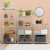 Three metal shelving units of varying heights are displayed against a light pink wall, filled with various decorative items and storage solutions. Podgląd zdjęcia produktu