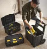 A man is kneeling and placing a yellow power tool into a black rolling toolbox. Two other black toolboxes are nearby. Voir les images du produit