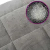 A close-up of a gray weighted blanket, showing its quilted texture and a magnified view of the filling material. Podgląd zdjęcia produktu