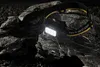 A Nitecore headlamp is placed on a dark, textured rock surface, with its light illuminating the area. Anteprima dell’immagine prodotto