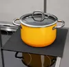 A yellow pot with a glass lid sits on a black mat placed on a stovetop. Produktbild-Vorschau