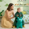 A mother and child are playing in a child's room decorated with dinosaur themes. The child is sitting on a green inflatable dinosaur toy. Podgląd zdjęcia produktu