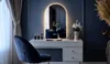 A modern vanity area with a makeup table, chair, and an arched LED mirror. Produktbild-Vorschau