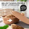 A terracotta bread pot filled with bread, with its lid partially open, set against a blurred background of kitchen items. Produktbild-Vorschau