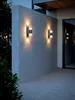 Two modern outdoor wall lights illuminate a concrete wall at dusk. Produktbild-Vorschau