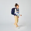 A young girl wearing a backpack and walking. Anteprima dell’immagine prodotto