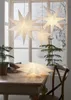 A festive indoor scene with paper stars hanging and resting on a wooden table, with a window showing a snowy outdoor view. Podgląd zdjęcia produktu