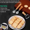 A collection of baking tools and freshly baked cookies are displayed on a plate, with a hand placing cookies into an oven in the background. Produktbild-Vorschau