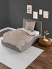 A bedroom scene with a single bed, bedding, and decorative items on the wall and floor. Produktbild-Vorschau