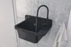 A black sink with a modern faucet is mounted on a tiled wall. A white towel hangs to the right. Náhled obrázku produktu