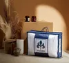 A product shot of a comforter in its packaging, styled with decorative elements like dried grasses and jars. Produktbild-Vorschau