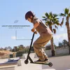 A young person riding a scooter in a skate park with palm trees in the background. Produktbild-Vorschau