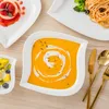 A table setting with various dishes, including soup, pasta, and dessert, arranged on white plates. Náhled obrázku produktu