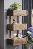 A rustic wooden wall shelf with three tiered boxes, decorated with plants and small glass bottles. Produktbild-Vorschau
