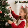 A young girl is decorating a Christmas tree with animal-shaped ornaments. Produktbild-Vorschau