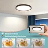 A ceiling light fixture is shown in a room, with a phone displaying the light's effect. Produktbild-Vorschau