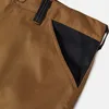 A close-up view of the pocket area of brown work pants with a black fabric insert. Produktbild-Vorschau
