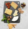 A cheese board with various cheeses, cherry tomatoes, olives, figs, nutmeg, basil, and crackers on a black cutting board. Produktbild-Vorschau