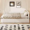 A daybed with a quilted blanket and pillows in a room with artwork on the wall and a patterned rug in the foreground. Voir les images du produit