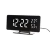 A digital alarm clock with a black mirrored display showing the time, temperature, and humidity. Produktbild-Vorschau
