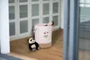 A child's laundry basket with a panda toy and a doll in a room with white cabinets. Produktbild-Vorschau