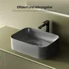A dark gray rectangular vessel sink with water swirling down the drain, placed on a light green vanity with ribbed detailing. Produktbild-Vorschau