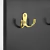 A close-up shot of a gold-colored hook mounted on a dark gray surface. Anteprima dell’immagine prodotto