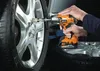 A person is using a cordless impact wrench to remove a lug nut from a car wheel. Produktbild-Vorschau