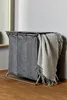 A grey laundry basket with a blanket draped over it, placed in a room with wooden flooring and a light grey wall. Produktbild-Vorschau