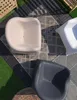 An overhead view of three modern outdoor chairs arranged on a patio with a patterned rug and decking. Produktbild-Vorschau