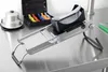 A professional studio shot of a mandoline slicer and its accessories on a stainless steel countertop. Produktbild-Vorschau