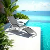 A chaise lounge chair is placed on a patio next to an infinity pool with a tropical ocean view. Náhled obrázku produktu