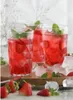 Three glasses of red strawberry drink with ice and mint leaves, garnished with strawberries, on a wooden tray. Voir les images du produit