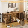 Two dogs are inside a large dog crate that doubles as a piece of furniture. The crate has a wooden top and black metal bars. There are decorative items on the top surface. Náhľad obrázku produktu