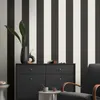 A room with striped wallpaper, a black dresser, and a black armchair. Produktbild-Vorschau