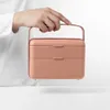 A person's hand is holding a pink lunchbox with a metal handle. Podgląd zdjęcia produktu