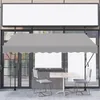An outdoor cafe setting with a gray awning over a table and chairs. Náhľad obrázku produktu