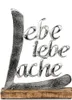 A decorative metal sign with words on a wooden base. Produktbild-Vorschau